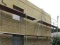 Kamienica w trakcie termomodernizacji, z widoczną wełną mineralną i rusztowaniami. Unijna dyrektywa EPBD wymusza te inwestycje.