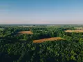 Krajobraz z lotu ptaka: lasy, pola uprawne i błękitne niebo. Idealne miejsce, by dowiedzieć się, jak sprawdzić status działki.
