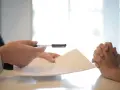 Sekrety weryfikacji najemcy: jak sprawdzić wiarygodność finansową bez BIK. Dłonie trzymają dokumenty i długopis.