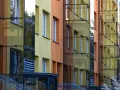 Nowoczesny blok z żółtymi i pomarańczowymi elewacjami, przeszklonymi klatkami schodowymi. Czy ustawa o windach wymusi montaż dźwigów w niskich blokach z czwartego piętra?