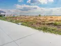 Budowa domu wkrótce? Zastanawiasz się, ile kosztuje metr działki budowlanej? Teren pod zabudowę z fundamentami i domami w tle.