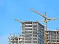Budowa wieżowca z dźwigami. Może to wyjaśniać, dlaczego deweloperzy unikają budowania mieszkań trzypokojowych w centrach miast – brakuje miejsca na tak duże inwestycje.