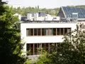 Nowe budynki od września 2026 będą musiały posiadać instalację fotowoltaiczną. Na dachu budynku widać panele i klimatyzatory.