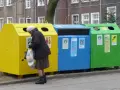 Starsza pani segreguje odpady przy kolorowych zsypach. Kto stoi za nowymi przepisami o segregacji odpadów w zsypach w starych blokach?