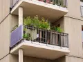 Po wypadkach, kto kontroluje stan techniczny balkonów w starych blokach? Ten balkon z panelami słonecznymi i kwiatami wygląda na zadbany.