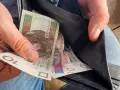 Ręka wyciąga polskie banknoty z portfela. Czy to wyjaśnia, dlaczego w marcu 2026 r. limity dochodowe do dodatku mieszkaniowego wzrosły o 20 proc.?