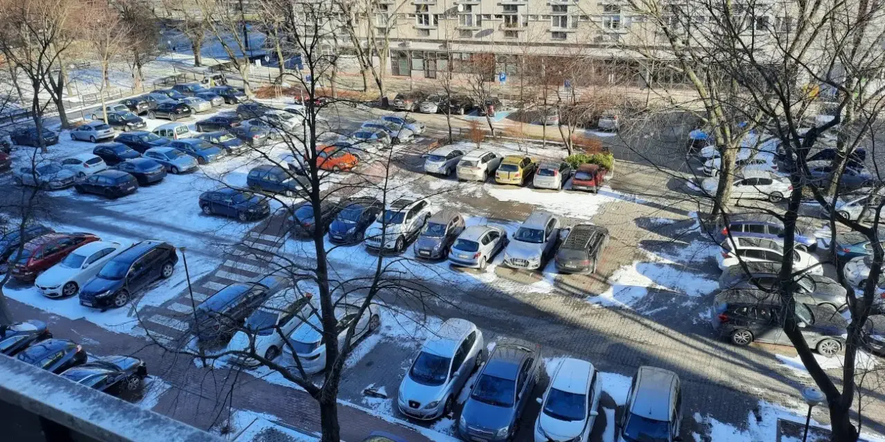 Zimowy parking pod blokiem z lat 90. pokazuje, dlaczego mieszkańcy mają problem z parkowaniem. Auta upchnięte na każdym wolnym skrawku ziemi.