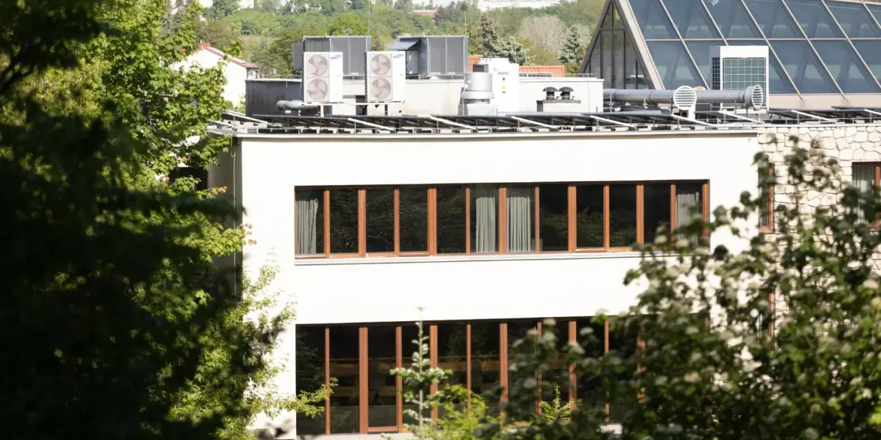 Nowe budynki od września 2026 będą musiały posiadać instalację fotowoltaiczną. Na dachu budynku widać panele i klimatyzatory.