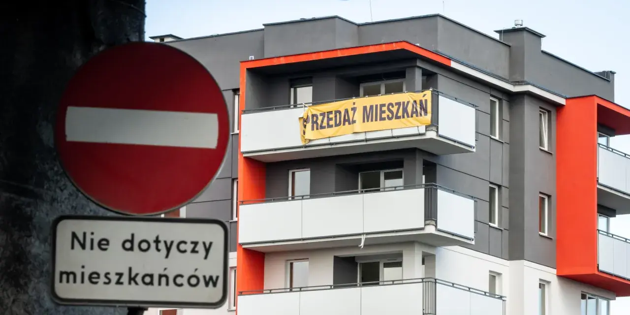 Baner "PRZEDAZ MIESZKAN" na nowoczesnym bloku. Czy to znak, dlaczego ceny mieszkań są tak wysokie?