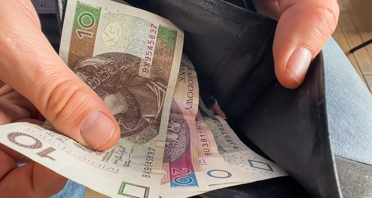 Ręka wyciąga polskie banknoty z portfela. Czy to wyjaśnia, dlaczego w marcu 2026 r. limity dochodowe do dodatku mieszkaniowego wzrosły o 20 proc.?