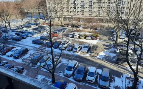 Zimowy parking pod blokiem z lat 90. pokazuje, dlaczego mieszkańcy mają problem z parkowaniem. Auta upchnięte na każdym wolnym skrawku ziemi.