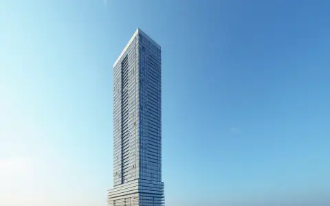 Nowoczesny wieżowiec z przeszkloną fasadą na tle błękitnego nieba. Trudno jednoznacznie określić, ile pięter ma ten skytower, ale z pewnością jest ich wiele.