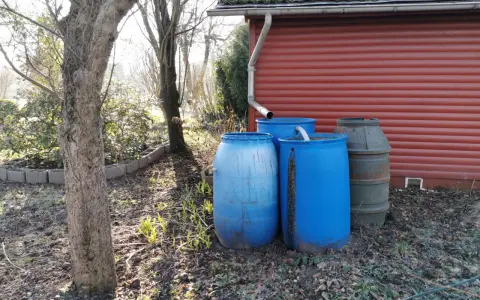 Zbiorniki na deszczówkę przy czerwonym budynku. Prawda o rzekomym opodatkowaniu deszczówki zbieranej na prywatnych posesjach jest taka, że nie ma takiego podatku.