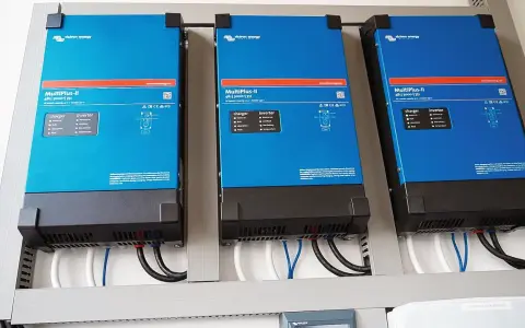 Trzy niebieskie falowniki Victron Energy MultiPlus-II zamontowane obok siebie. Od września 2026 r. każdy blok musi posiadać certyfikowany magazyn energii.