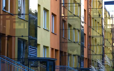 Nowoczesny blok z żółtymi i pomarańczowymi elewacjami, przeszklonymi klatkami schodowymi. Czy ustawa o windach wymusi montaż dźwigów w niskich blokach z czwartego piętra?