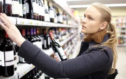 Kobieta wybiera wino, zastanawiając się, czy gmina może zmienić limity odległości od szkół dla konkretnej działki.
