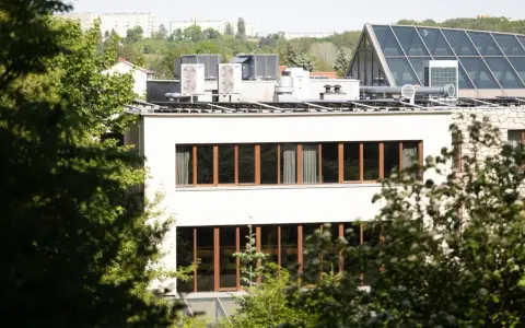 Nowe budynki od września 2026 będą musiały posiadać instalację fotowoltaiczną. Na dachu budynku widać panele i klimatyzatory.