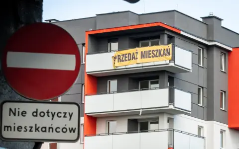 Baner "PRZEDAZ MIESZKAN" na nowoczesnym bloku. Czy to znak, dlaczego ceny mieszkań są tak wysokie?