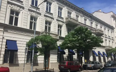 Kamienica z balkonami i niebieskimi markizami. Zastanawiasz się, dlaczego koszt czynszu w blokach z 2026 roku jest wyższy niż w kamienicach?