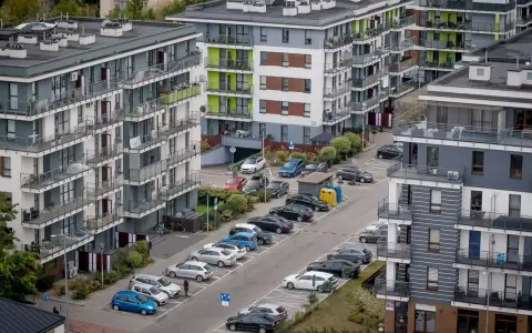 Nowy blok mieszkalny z balkonami i samochodami na parkingu. Kto musi zapłacić 64 tysiące złotych kary za uchylanie się od podatku od nieruchomości?