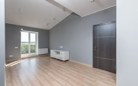 Puste, szare pomieszczenie z drzwiami i oknem. Idealne miejsce na pierwsze mieszkanie TBS, gdy już wiesz, jak dostać mieszkanie TBS.