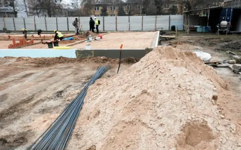 Budowa w marcu 2026. Działka z uregulowanym stanem prawnym, przygotowana pod fundamenty. Piasek, zbrojenie i pracownicy na placu budowy.