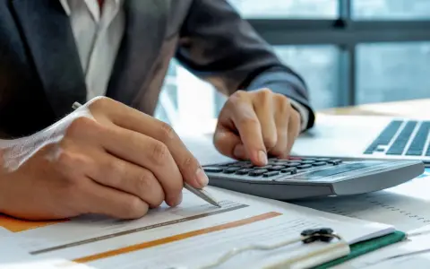 Analiza finansowa kluczem do tego, jak zarobić na wynajmie mieszkania. Ręce liczą koszty i zyski.