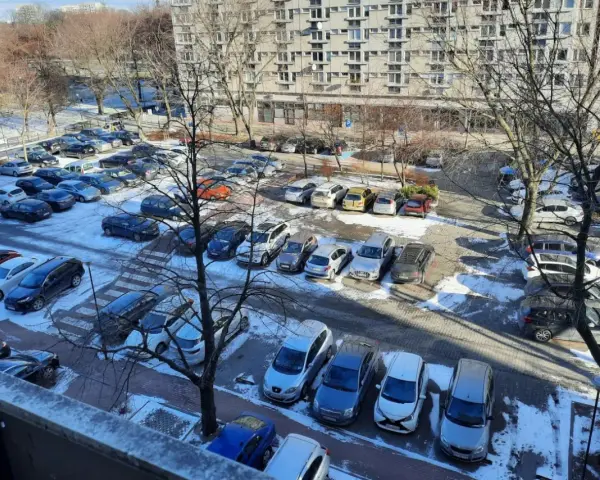 Zimowy parking pod blokiem z lat 90. pokazuje, dlaczego mieszkańcy mają problem z parkowaniem. Auta upchnięte na każdym wolnym skrawku ziemi.