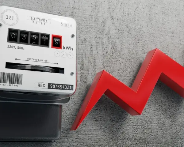 Licznik energii elektrycznej i czerwona strzałka w górę symbolizują, dlaczego koszt doprowadzenia prądu do działki wzrósł o 20 procent w 2026 roku.