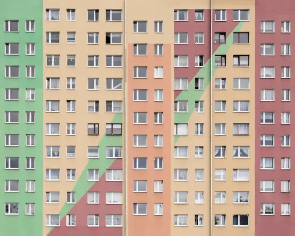 Wielopiętrowy blok mieszkalny w kolorach pastelowych. Szukasz informacji, jak wynająć mieszkanie komunalne?