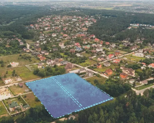 Działki bez planu ogólnego gminy będą niesprzedawalne od lipca 2026. Aerial view of suburban housing development with a highlighted plot of land.
