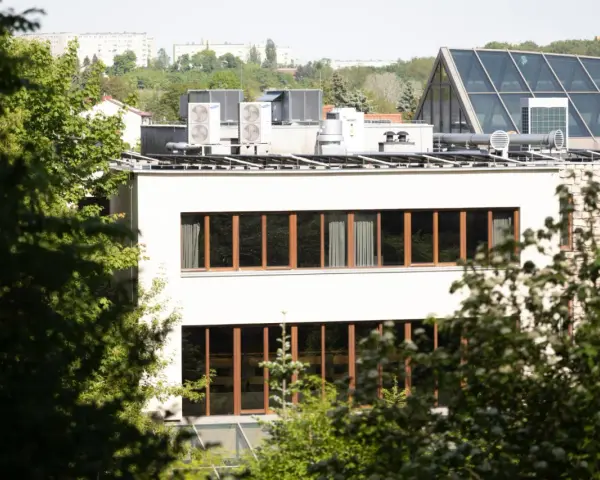 Nowe budynki od września 2026 będą musiały posiadać instalację fotowoltaiczną. Na dachu budynku widać panele i klimatyzatory.