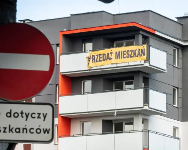 Baner "PRZEDAZ MIESZKAN" na nowoczesnym bloku. Czy to znak, dlaczego ceny mieszkań są tak wysokie?