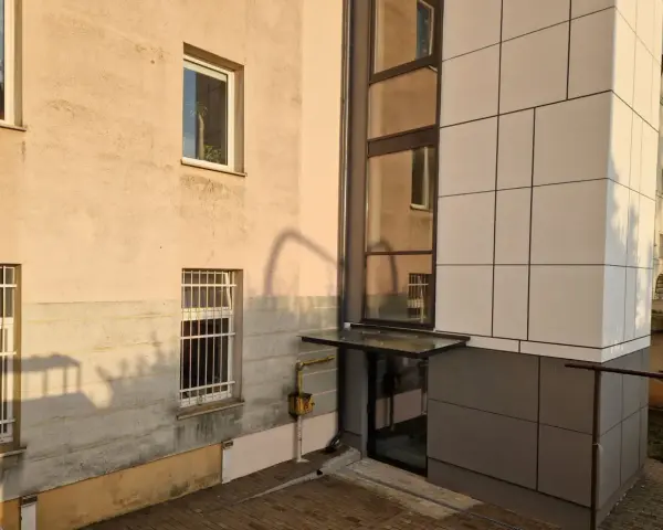 Nowoczesna elewacja bloku z nową windą zewnętrzną. Dowiedz się, ile kosztuje wymiana windy w bloku.