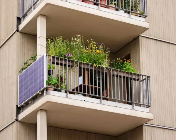 Po wypadkach, kto kontroluje stan techniczny balkonów w starych blokach? Ten balkon z panelami słonecznymi i kwiatami wygląda na zadbany.