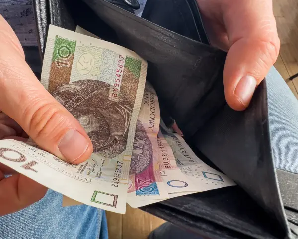 Ręka wyciąga polskie banknoty z portfela. Czy to wyjaśnia, dlaczego w marcu 2026 r. limity dochodowe do dodatku mieszkaniowego wzrosły o 20 proc.?