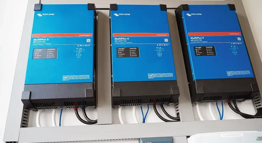 Trzy niebieskie falowniki Victron Energy MultiPlus-II zamontowane obok siebie. Od września 2026 r. każdy blok musi posiadać certyfikowany magazyn energii.