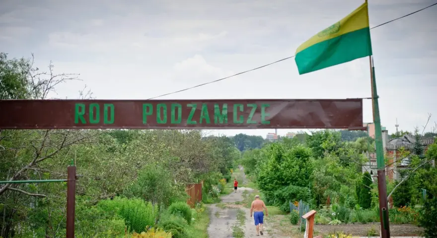 Kto stoi za kampanią "wolne działki ROD"? Czy protesty zablokują nowe przepisy? Wjazd do ROD Podzamcze, gdzie widać mężczyznę idącego ścieżką.