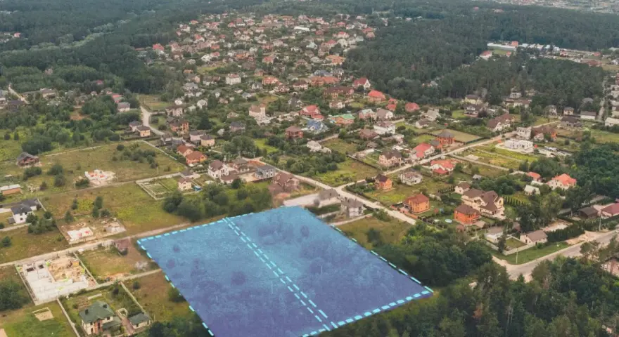 Działki bez planu ogólnego gminy będą niesprzedawalne od lipca 2026. Aerial view of suburban housing development with a highlighted plot of land.