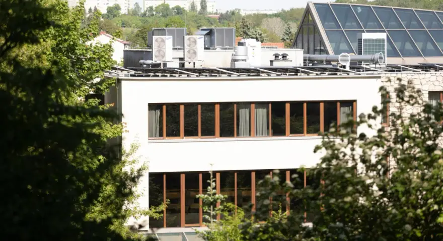 Nowe budynki od września 2026 będą musiały posiadać instalację fotowoltaiczną. Na dachu budynku widać panele i klimatyzatory.
