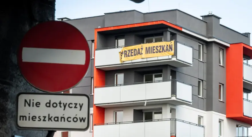 Baner "PRZEDAZ MIESZKAN" na nowoczesnym bloku. Czy to znak, dlaczego ceny mieszkań są tak wysokie?