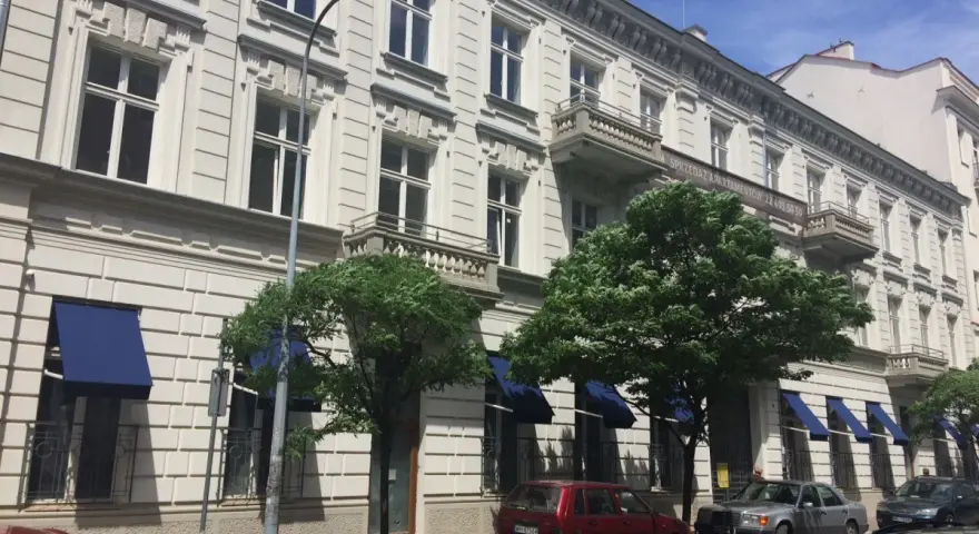 Kamienica z balkonami i niebieskimi markizami. Zastanawiasz się, dlaczego koszt czynszu w blokach z 2026 roku jest wyższy niż w kamienicach?