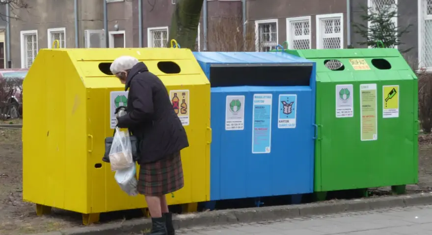Starsza pani segreguje odpady przy kolorowych zsypach. Kto stoi za nowymi przepisami o segregacji odpadów w zsypach w starych blokach?