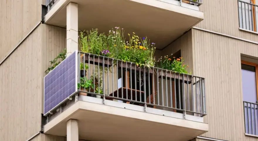 Po wypadkach, kto kontroluje stan techniczny balkonów w starych blokach? Ten balkon z panelami słonecznymi i kwiatami wygląda na zadbany.