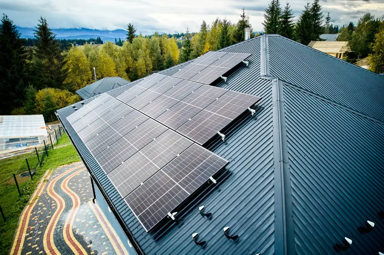Panele fotowoltaiczne na dachu domu w górskim krajobrazie. Od września 2026 każdy nowy budynek musi posiadać instalację fotowoltaiczną, by czerpać energię ze słońca.