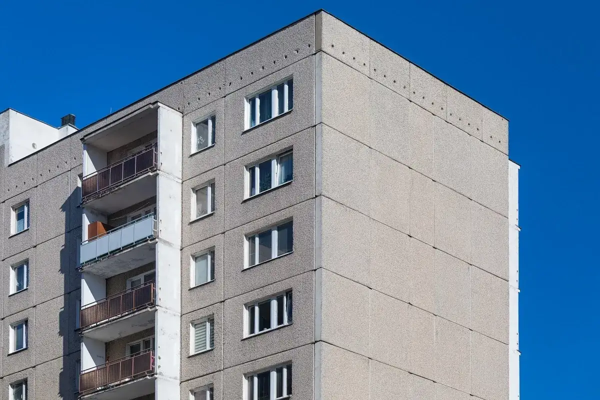 Szary blok z wielkiej płyty pod błękitnym niebem. Zastanawiasz się, dlaczego w 2026 roku mieszkania w blokach z cegły drożeją szybciej niż te z płyty?