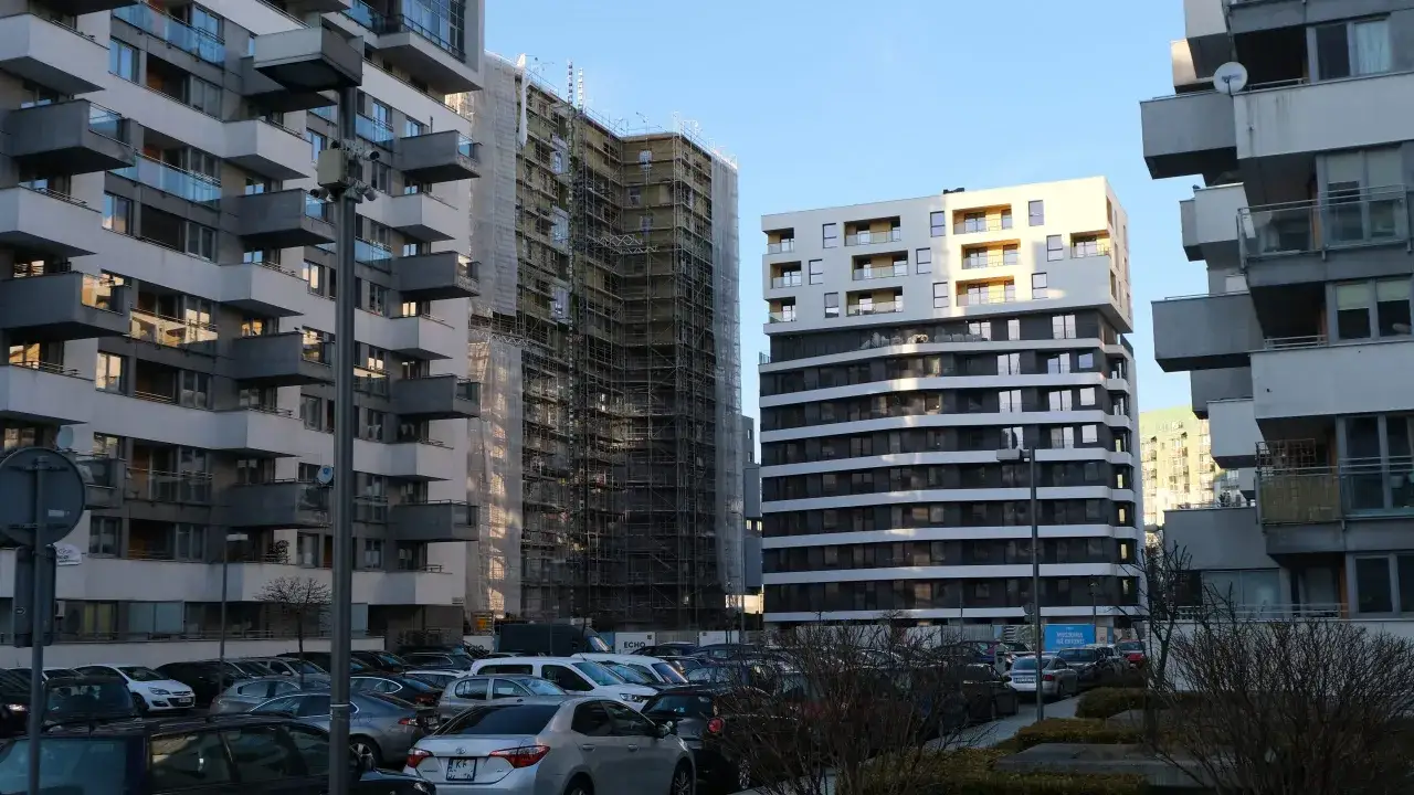 Nowe osiedla w 2026 r. – dlaczego mieszkańcy masowo skarżą się na patodeweloperkę? Widok na budynki mieszkalne i parking.
