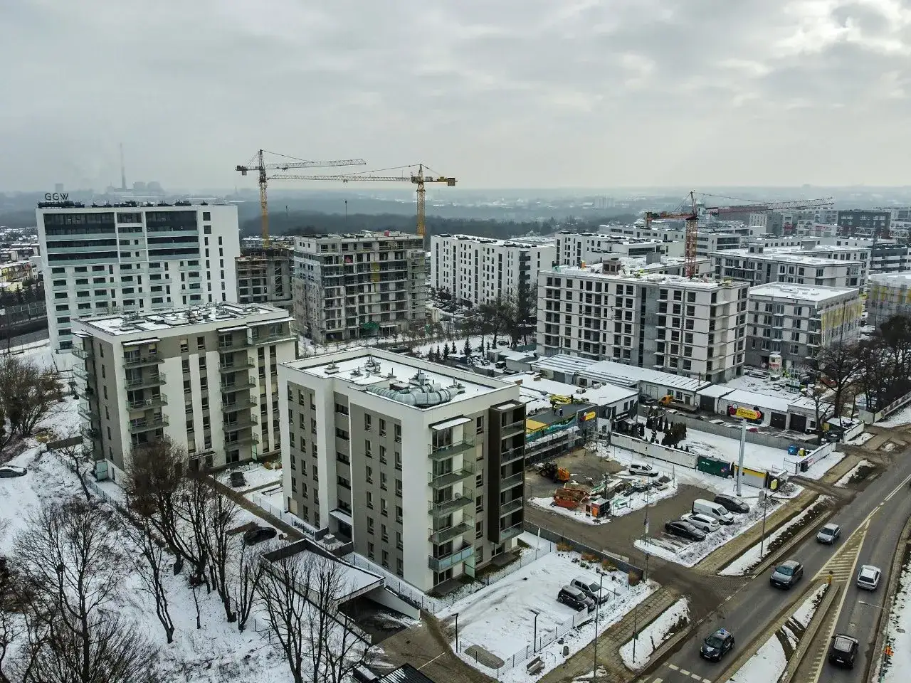 Prawda o rzekomym podatku od pustostanów dla właścicieli więcej niż trzech mieszkań. Nowe osiedle w zimowej scenerii, z dźwigami budowlanymi w tle.