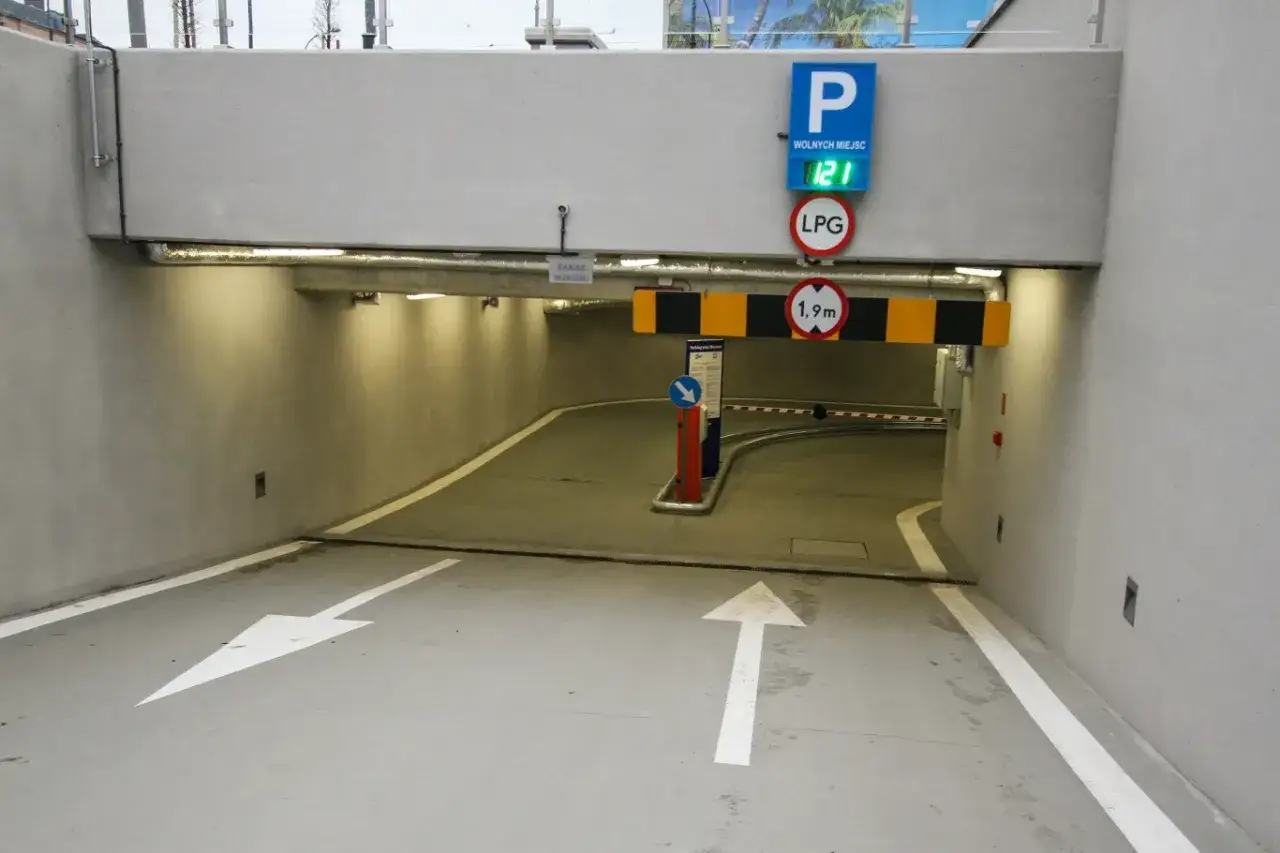 Czy parkingi podziemne w blokach są bezpieczne dla samochodów elektrycznych w 2026? Wjazd do podziemnego parkingu z ograniczeniem wysokości 1,9m.