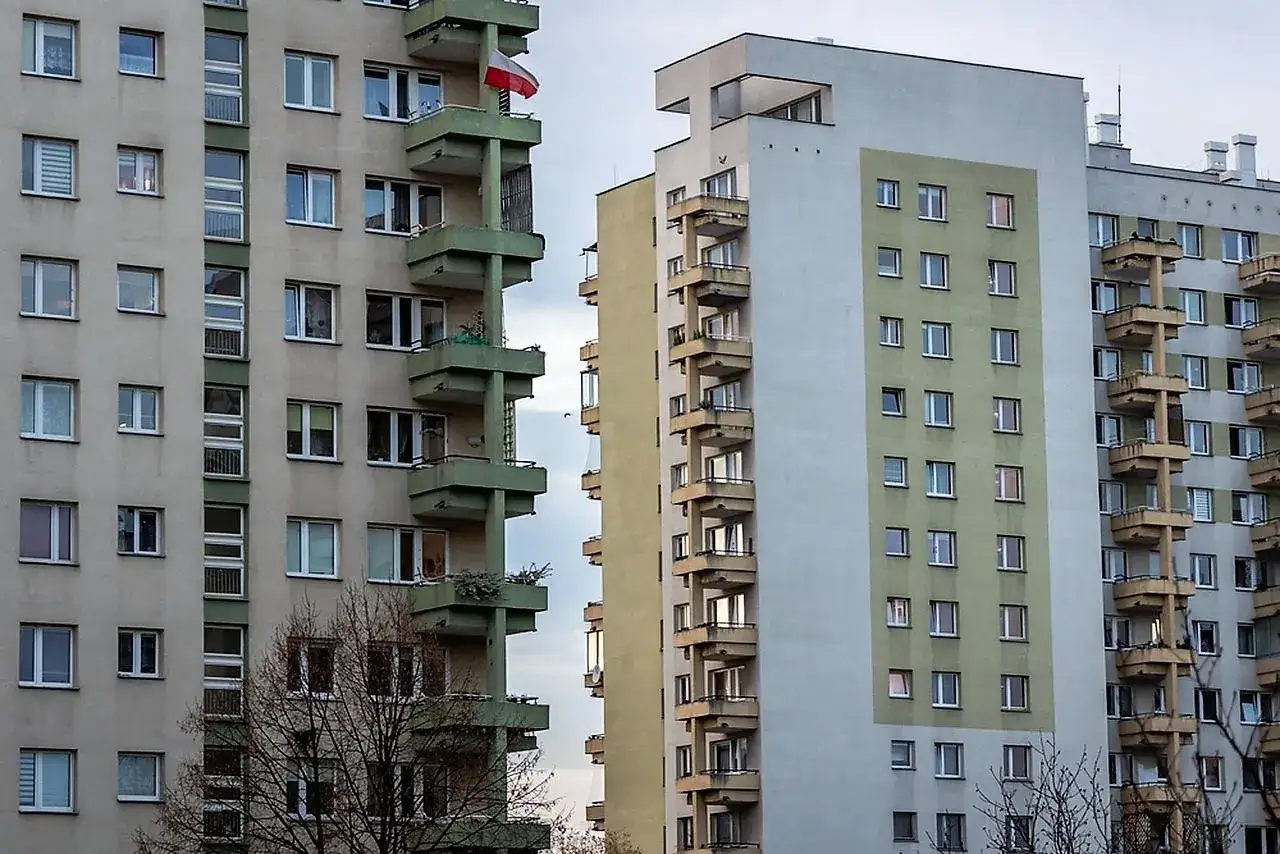 Bloki z cegły, z polską flagą na balkonie, mogą być odpowiedzią na pytanie, dlaczego w 2026 roku mieszkania w blokach z cegły drożeją szybciej niż te z płyty.